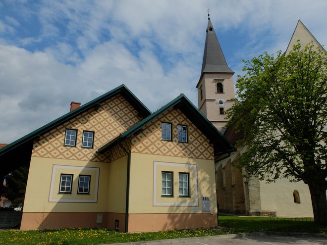 Nemška hiša v Apačah, v kateri ima sedež Kulturno društvo Apaško polje, ob njej cerkev Marijinega vnebovzetja. FOTO Iztok Ilich
