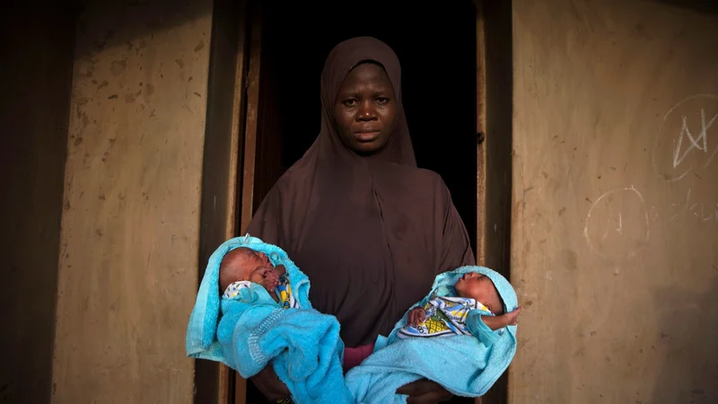 Fotografija: Muslimanka v rokah drži štiri dni stara identična dvojčka pred vhodom v svojo hišo v Igbo Ori. Foto Afolabi Sotunde Reuters