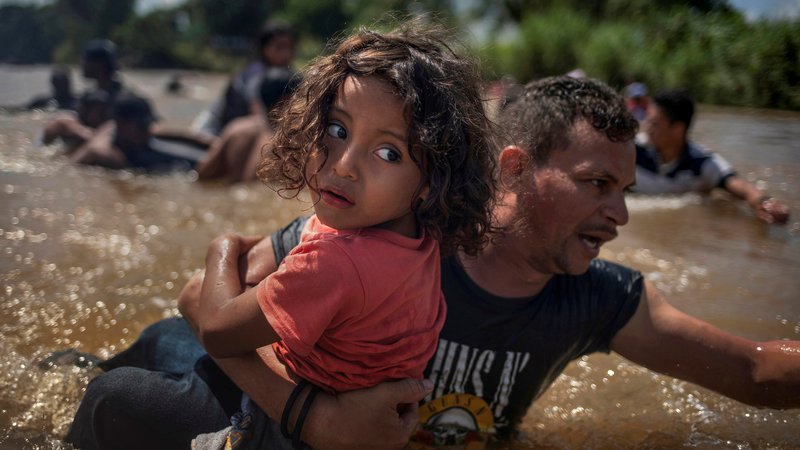 Fotografija: Luis Acosta iz Hondurasa nosi 5-letnega Anhela Jezusa med prečkanjem reke Suchiate na meji med Gvatemalo in Mehiko, skupaj z ostalo karavano priseljencev iz Srednje Amerike na poti v ZDA. Foto Adrees Latif Reuters