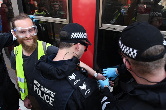 Na današnjem protestu se je moški na sliki s super lepilom prilepil na vrata stoječega vlaka. FOTO: Daniel Leal-olivas/Afp