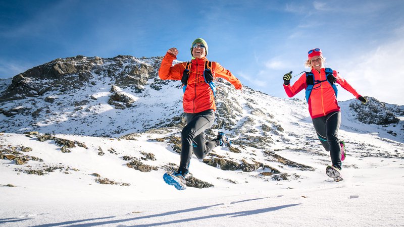 Fotografija: Two runners laughing while running downhill  on the Piz Lunghin above Maloja, Switzerland after an early winter snow storm.
