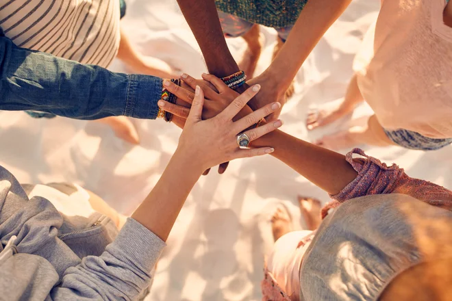 Closeup image of hands of young people with on stack. Group of mixed race friends on the beach with their hands stacked.
