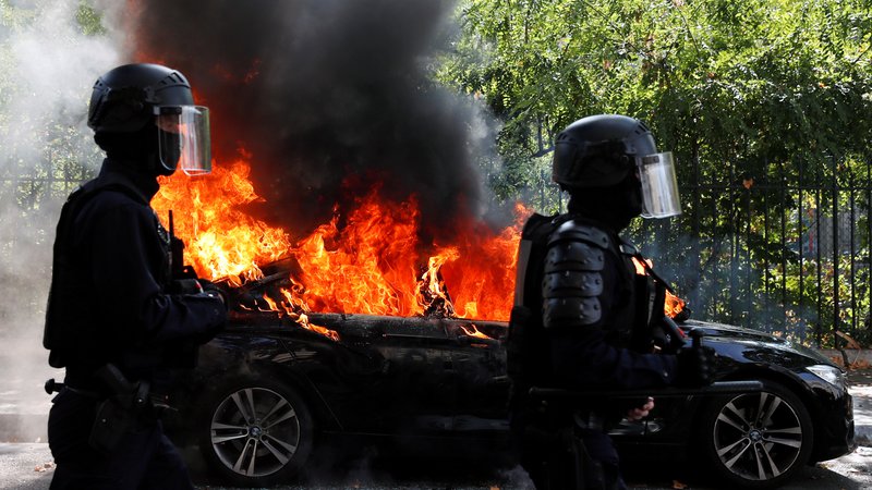 Fotografija: Francoski policisti ob zažganem avtomobilu med današnjim protestom rumenih jopičev v Parizu. FOTO: Gonzalo Fuentes/Reuters