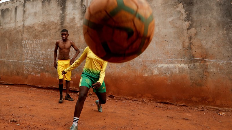 Fotografija: Kamerunka Gaelle Dule Asheri, 17-letna nogometašica, ki je med prvimi valovi deklet, katere usposabljajo profesionalni trenerji na Rails Foot Academy, igra nogomet s svojimi prijatelji pred svojo hišo v Yaoundeju. Asheri ni nikoli obupala kljub močnemu nasprotovanju njene matere, ki se je bala, da bi izgubila hčerko zaradi moške igre. Ko je prvič začela igrati nogomet na umazanih ulicah blizu svojega doma, je bila edina deklica v soseski. »Pobrala sem žogo, jo brcnila in nikoli nisem pogledala nazaj.« FOTO: Zohra Bensemra/Reuters