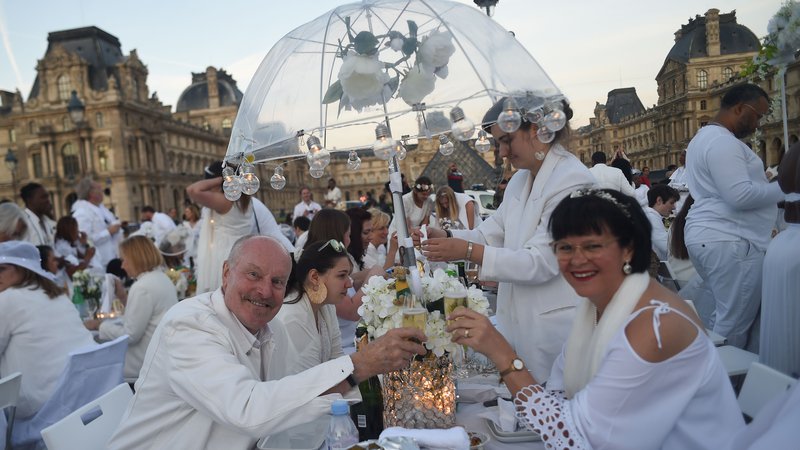 Fotografija: Ljudje, oblečeni v belo, na 31. izdaji prireditve Večerja v belem (Diner en blanc) v Pariških vrtovih Tuileries v Parizu. Prireditev je skrivni stilski fenomen, ki se je začel v Franciji in se razširil po vsem svetu. FOTO: Lucas Barioulet/AFP