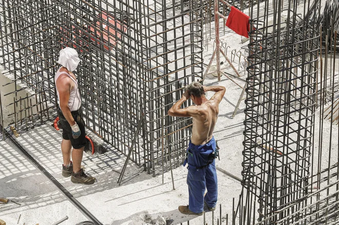 Pravilnik o varnem delu določa, da je treba intenzivnost dela zmanjšati ali delo prekiniti, ko se temperature zvišajo nad 28 stopinj Celzija, a nekateri delavci na gradbišču hotela delajo tudi v najhujši vročini. FOTO: Leon Vidic