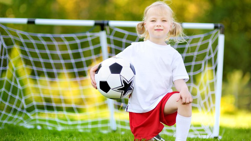 Fotografija: Cute little soccer player having fun playing a soccer game on sunny summer day