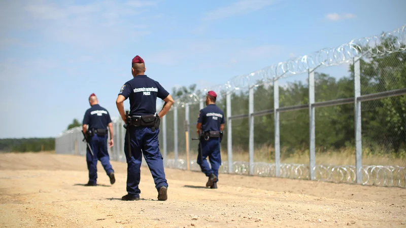 Fotografija: Madžarski policisti ob 175m dolgi ograji ki stoji na madžarsko-srbski meji. Pri kraju Morahalom, Madžarska, 30.julija 2015.
[Policisti, Madžarska, Srbija, Morahalom, ograje, državne meje]