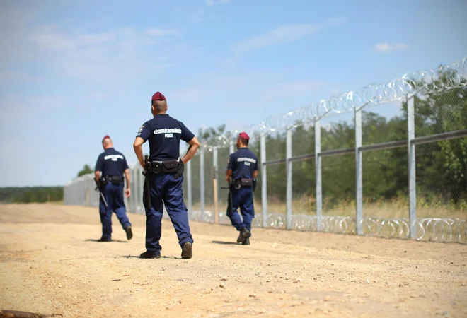Madžarski policisti ob 175m dolgi ograji ki stoji na madžarsko-srbski meji. Pri kraju Morahalom, Madžarska, 30.julija 2015.
[Policisti, Madžarska, Srbija, Morahalom, ograje, državne meje]