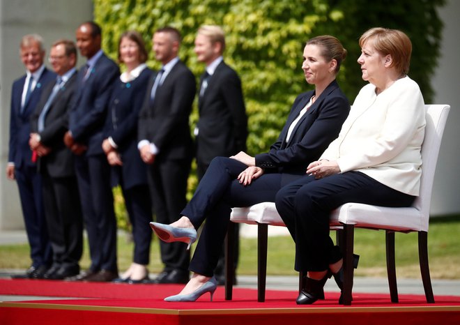 Angela Merkel in danska premierka Mette Frederiksen sta himno poslušali sede. FOTO: Hannibal Hanschke/Reuters