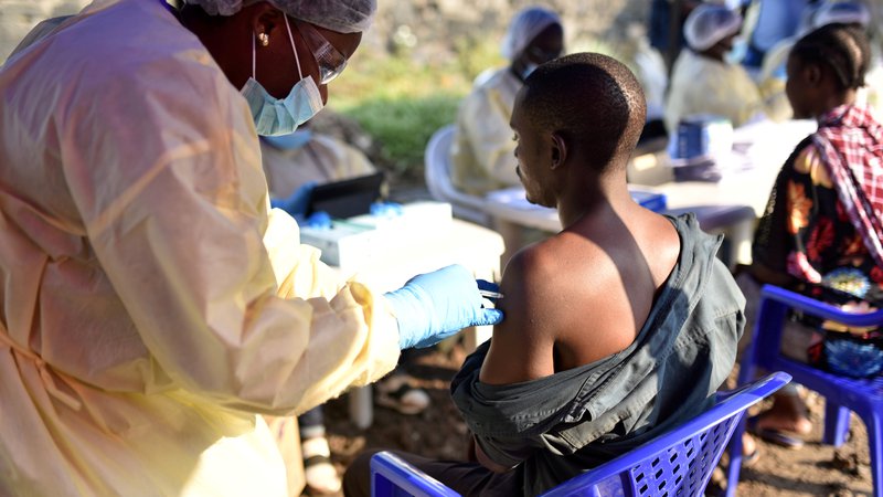 Fotografija: Kongovski zdravstveni delavec daje cepivo ebole moškemu v zdravstvenem centru Himbi v Gomi. FOTO: Olivia Acland/Reuters
