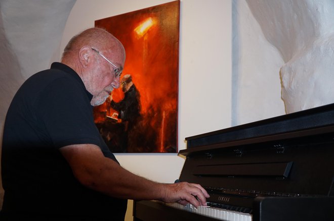 Igor Orešič, organizator slovenske udeležbe v Parizu, je na odprtju razstave udeležencev na Velenjskem gradu zaigral na klavir pod svojim avtoportretom <em>Pianist</em>. FOTO: Brane Piano