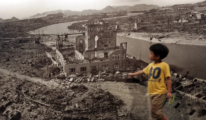 Deček pred fotografijo Hirošime leta 1945, ko jo je opustošila atomska bomba. FOTO: Reuters