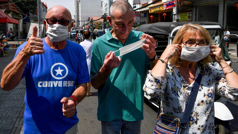 Fotografija: Strah pred novim virusom se širi po Aziji. Na fotografiji so turisti z zaščitnimi maskami v glavnem mestu Kambodže Phnom Penhu, kjer so ta teden uradno potrdili prvi primer okužbe. FOTO: AFP