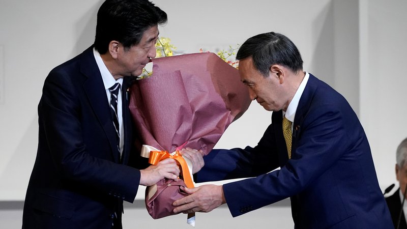 Fotografija: Nekdanji in bodoči premier Japonske Šinzo Abe in Jošihide Suga. FOTO:  Eugene Hoshiko/Reuters