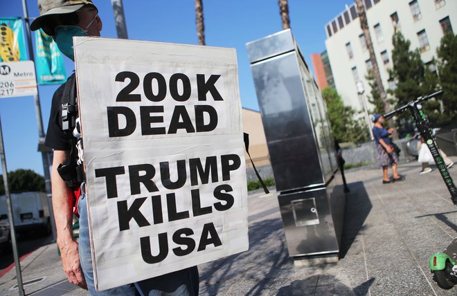 Protestnik opozarja na število smrti v ZDA in zanje krivi predsednika Donalda Trumpa. FOTO: Mario Tama/AFP