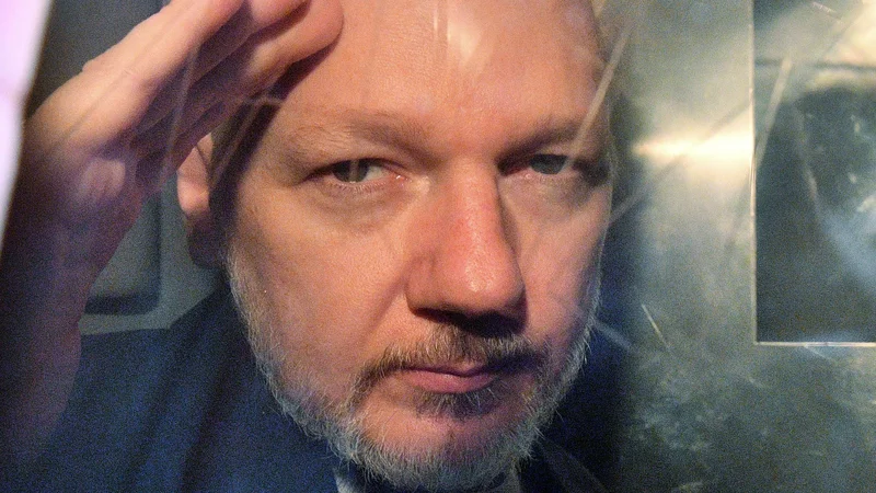 Fotografija: Julian Assange, fotografiran v policijskem vozilu na poti s sodišča Southwark Crown Court 1. maja lani. FOTO: Daniel Leal-Olivas/AFP