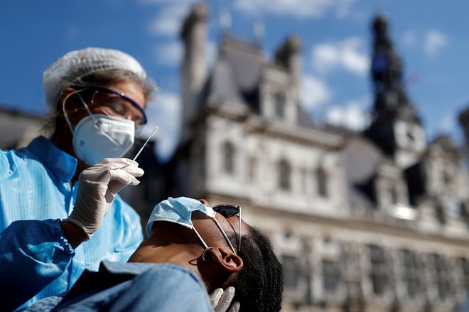 Jemanje vzorcev za testiranje okužb pred mestno hišo v Parizu. FOTO: Christian Hartmann/Reuters