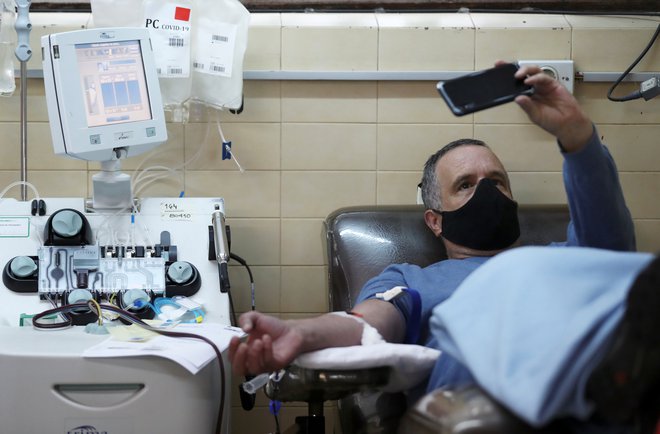 Argentinec, ki je okreval po okužbi, med doniranjem krvi na inštitutu v La Plati v Argentini. FOTO: Agustin Marcarian/Reuters