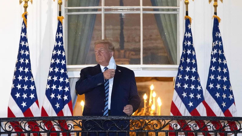 Fotografija: Ameriški predsednik Donald Trump si je po prihodu iz bolnišnice pred Belo hišo demonstrativno odstranil zaščitno masko. FOTO: Win McNamee/AFP