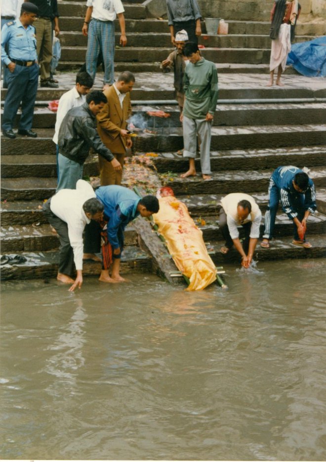 Pogrebci v Nepalu nosilo s truplom najprej položijo k vodi, vanjo namočijo njegove noge, ga polivajo in prižigajo paličice. FOTO: Alen Steržaj