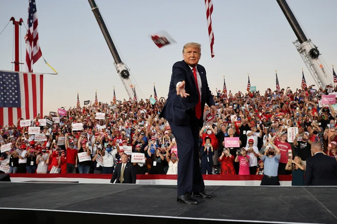 Pandemija je Donaldu Trumpu otežila briljiranje na množičnih predvolilnih zborih, a predsednik ni obupal. Na Floridi je metal privržencem zaščitne maske. FOTO: Jonathan Ernst/Reuters
