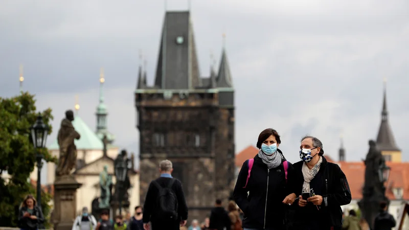 Fotografija: Po Karlovem mostu v Pragi se lahko ljudje sprehajajo le v zaščitnih maskah. Foto: David W Cerny/Reuters