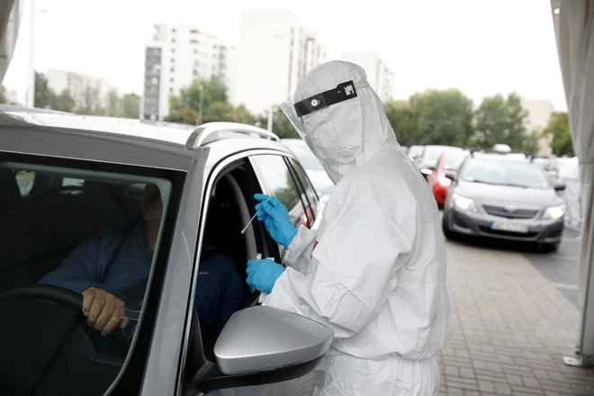 Osebje v zaščitni obleki med testiranjem na koronavirus v Varšavi. FOTO: Kacper Pempel/Reuters