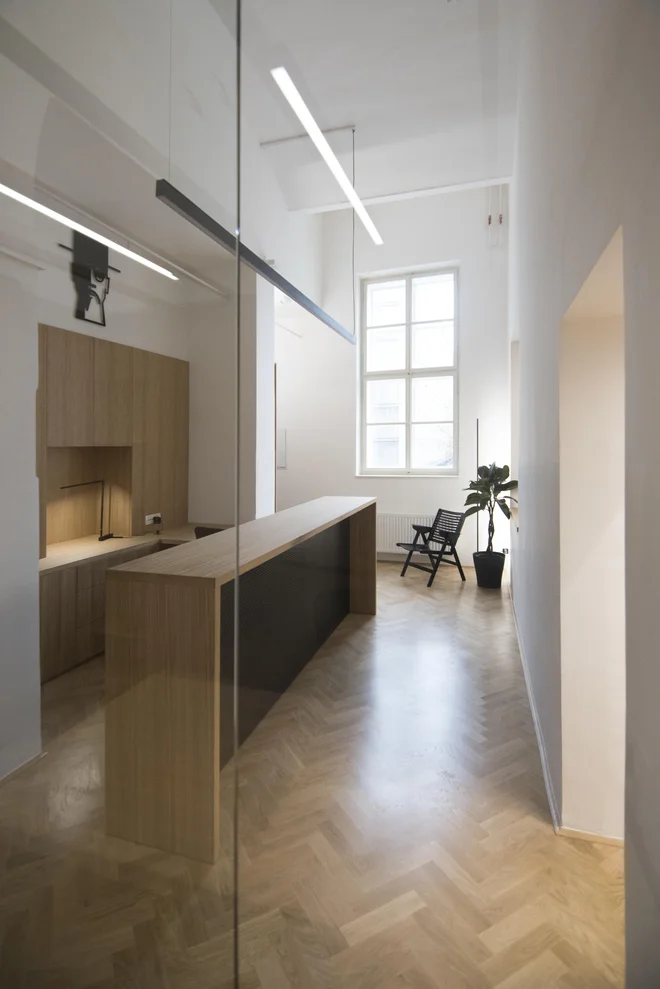Po odstranitvi predelnih sten hišniškega stanovanja sta se pokazala vstopni, ožji in členjen prostor, kamor je odslej umeščen izposojevalni pult, ter večji, enovit in svetel prostor. FOTO: Nika Curk