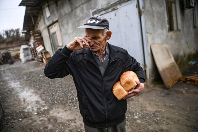 Starejši moški prejme brezplačen kruh iz pekarne v mestu Stepanakert. Pekarna 24 ur na dan ponuja kruh prebivalcem in ga po potrebi dostavi v oblegani mesti Martuni in Martakert med nenehnimi spopadi Armenije in Azerbajdžanom zaradi odcepljenega območja Gorskega Karabaha. FOTO: Aris Messinis/Afp