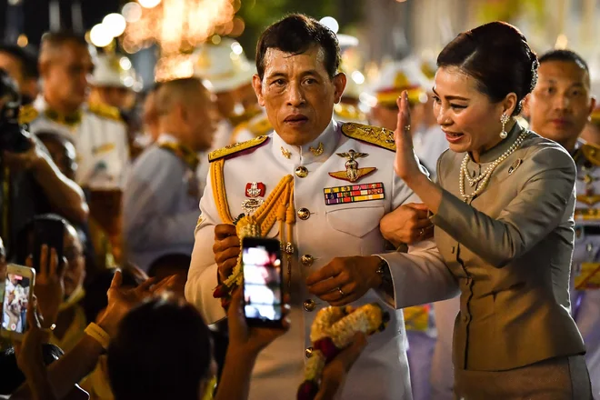 Tajski kralj Maha Vajiralongkorn in kraljica Suthida pozdravljata rojalistične pristaše pred Veliko palačo v Bangkoku, potem ko sta predsedovala verski slovesnosti v budističnem templju v palači. FOTO: Lillian Suwanrumpha/Afp