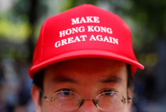 Številni hongkonški aktivisti te dni nosijo rdeče kape s ščitnikom in napisom &raquo;Naredimo Hongkong znova velik!&laquo;. FOTO: Kai Pfaffenbach/Reuters