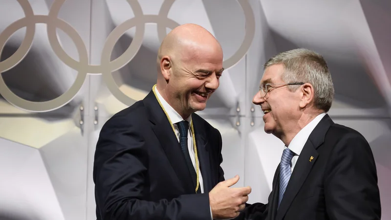 Fotografija: Ne le predsednik Mednarodnega olimpijskega komiteja Thomas Bach (desno), tudi prvi mož Svetovne nogometne zveze in član IO Moka Gianni Infantino upa, da bo cepivo proti koronavirusu čim hittreje prišlo do športnikov. FOTO: Fabrice Coffrini/AFP