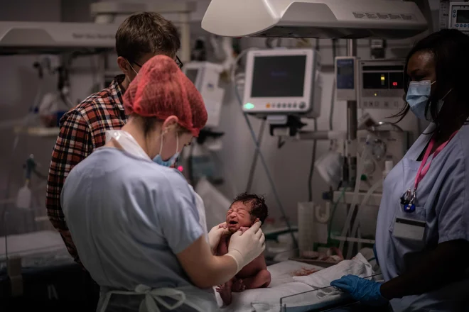 Medicinske sestre skrbijo za novorojenčka med pandemijo v porodnišnici Diacoases v Parizu. FOTO: Martin Bureau/Afp