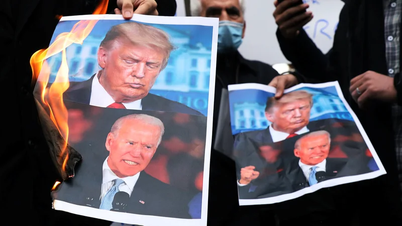 Fotografija: Protestniki zaradi atentata na jedrskega znanstvenika Fahrizadeha v Teheranu zažigajo fotografije Donalda Trumpa in Joeja Bidna.
Foto Wana/Reuters