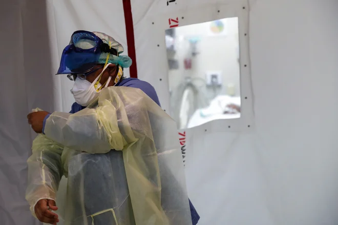 Medicinska sestra pred izolacijsko sobo enote za intenzivno nego v bolnišnici Roseland Community Hospital v Chicagu. FOTO: Shannon Stapleton/Reuters