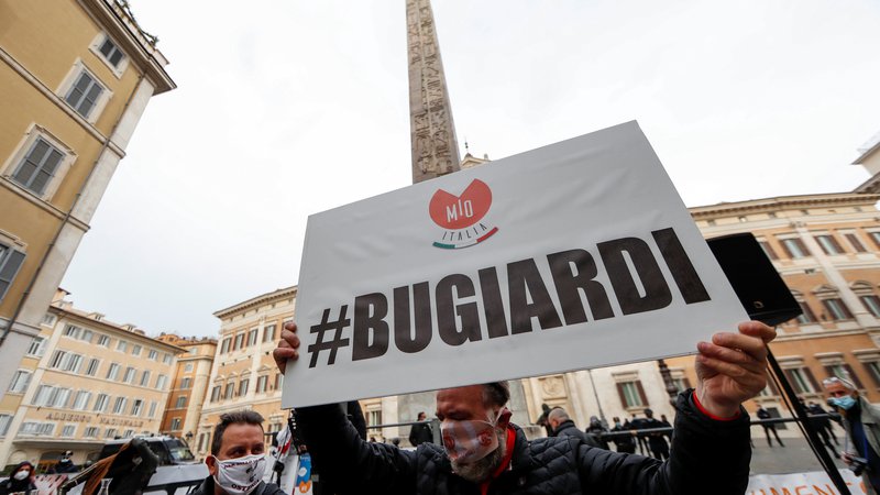 Fotografija: Nasprotnik ukrepov za preprečitev širjenja okužb med protestom pred sedežem spodnjega doma italijanskega parlamenta v Rimu. V rokah drži transparent z napisom »lažnivci«. Foto: Yara Nardi/Reuters