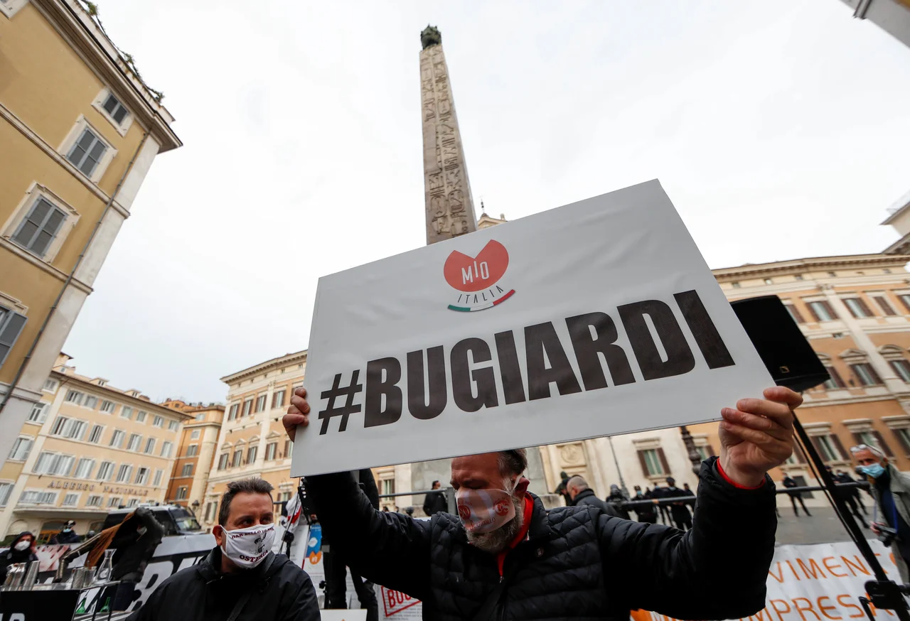 Fotografija: Nasprotnik ukrepov za preprečitev širjenja okužb med protestom pred sedežem spodnjega doma italijanskega parlamenta v Rimu. V rokah drži transparent z napisom »lažnivci«. Foto: Yara Nardi/Reuters