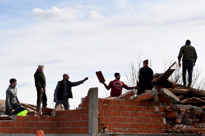 Prostovoljci odstranjujejo dele poškodovanih streh. FOTO: Denis Lovrović/AFP