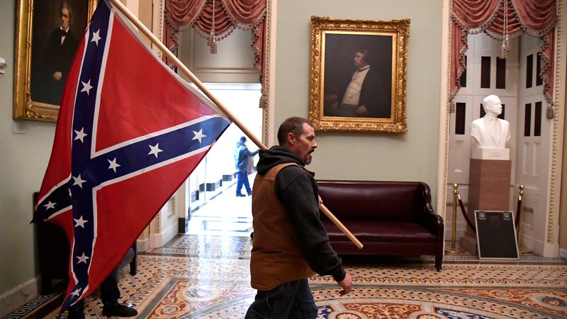 Fotografija: Podpornik odhajajočega predsednika s konfederalno zastavo po vdoru v kongresno stavbo. 
FOTO: Mike Theiler/Reuters
