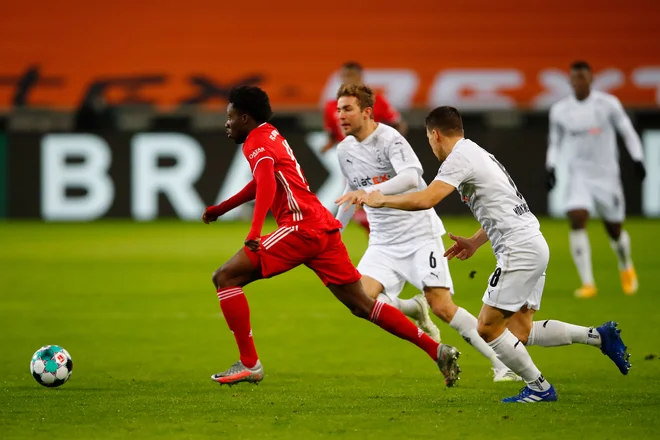 Nogometaši Bayerna (na fotografiji Alphoso Davies) in Mönchengladbacha (Christoph Kramer in Stefan Lainer) so uprizorili zelo razburljivo nogometno predstavo. FOTO: Wolfgang Rattay/AFP