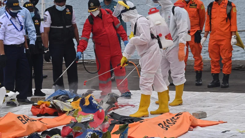 Fotografija: Pripadniki indonezijskega Rdečega križa ob predmetih, ki so bili na letalu družbe Sriwijaya Air. FOTO: Adek Berry/AFP