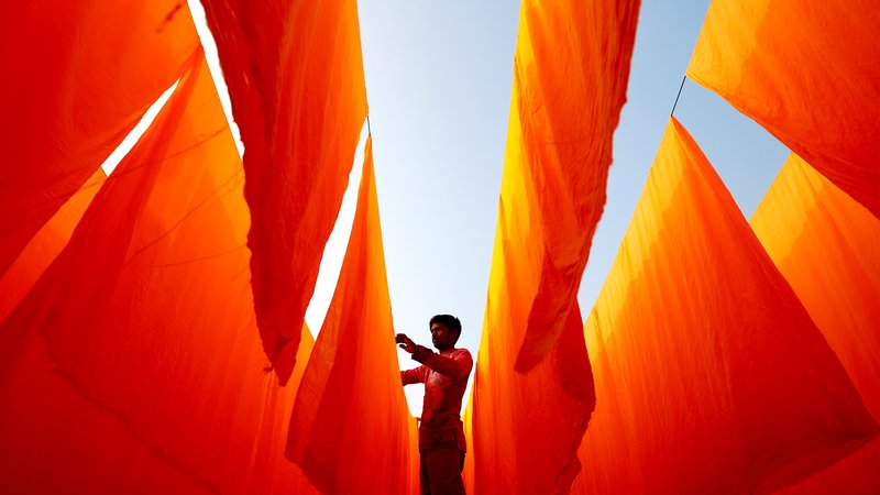 Fotografija: Bangladeški delavec suši tkanine po nanosu barve v tovarni barvil v Narayanganju. FOTO: Mohammad Ponir Hossain/Reuters