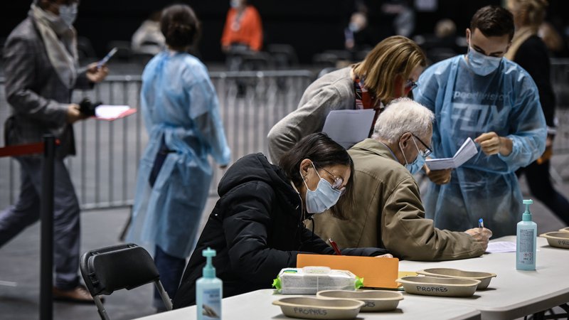 Fotografija: Ljudje izpolnjujejo obrazce pred cepljenjem v francoskem Lyonu. FOTO: Jean-philippe Ksiazek/AFP