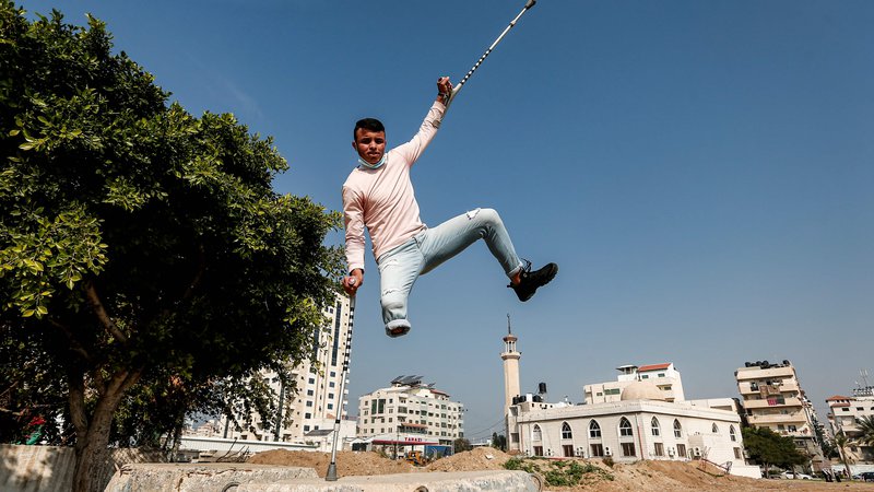 Fotografija: Palestinskemu najstniku je izstrelek odnesel nogo, a se priljubljeni dejavnosti ni odpovedal. FOTO: Mahmud Hams/AFP
