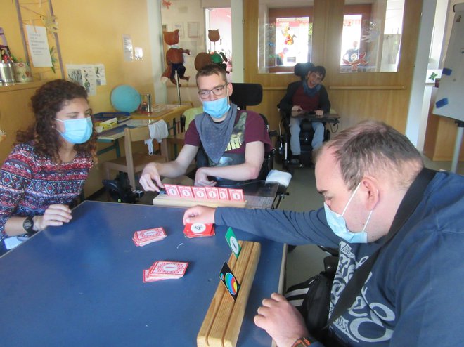 Prostovoljka iz Portugalske in mladostnika pri igranju kart. FOTO: Cirius Kamnik