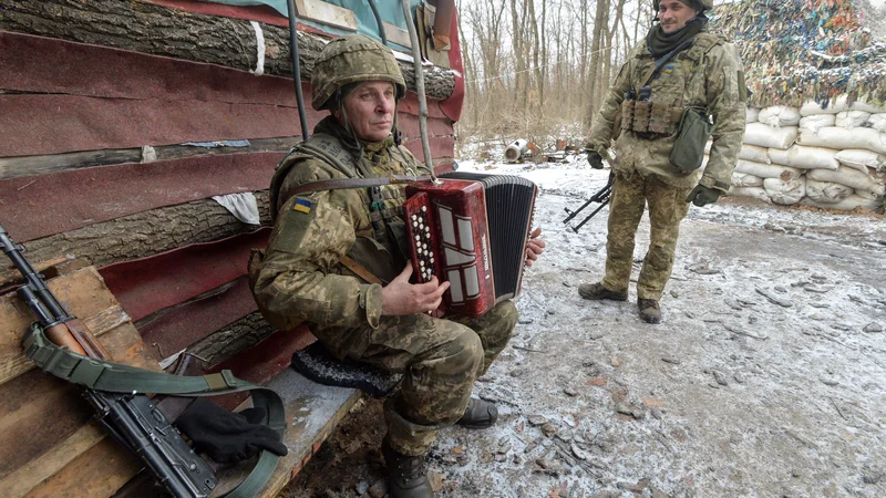 Fotografija: Ukrajinski vojak igra harmoniko na bojnih položajih v bližini mesta Avdiivka v Donjecku, kjer potekajo boji z rusko podprtimi separatističnimi uporniki. FOTO: Oleksandr Klymenko/Reuters