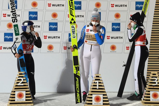 Z naslovom svetovne prvakinje se je ovenčala Norvežanka Maren Lundby (na sredini), ki ji je ob bronasti Niki Križnar (desno) družbo na odru za najboljše delala tudi srebrna Japonka Sara Takanaši (levo). FOTO: Christof Stache/AFP