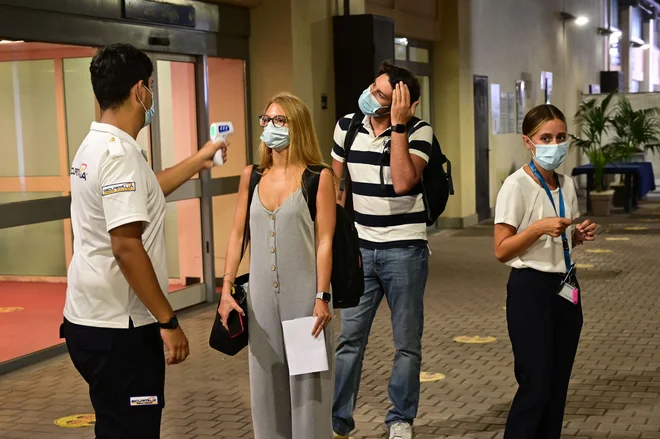 Potnikom pred vkrcanjem izmerijo temperaturo, vstopijo lahko le, če so brez znakov prehlada in imajo negativen test na covid, potem pa morajo upoštevati pravila, ki veljajo na ladji. FOTO: Miguel Medina/AFP