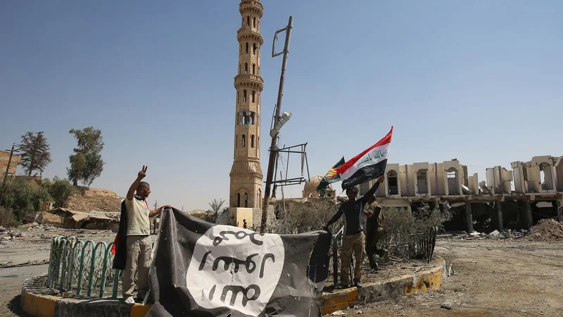 Fotografija: Moška ob zastavi, ki jo je med osvobajanjem območja Tal Afar v Siriji leta 2017 zapustila Islamska država. FOTO: Ahmad Al-rubaye/AFP